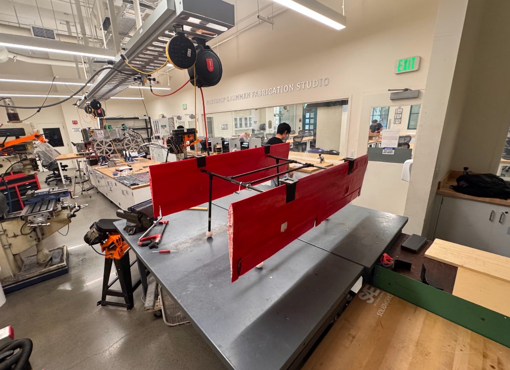 Red airframe assembly positioned in fabrication workshop