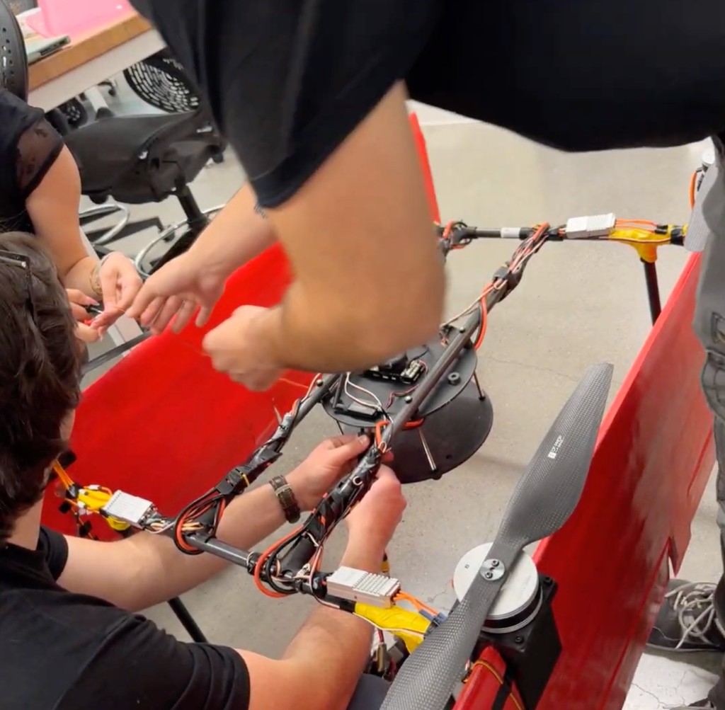 Team members routing and securing wiring on the VTOL airframe